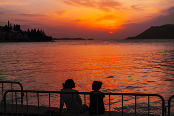 Naklejka na ściany i meble Young couple sitting on the beach near the sea