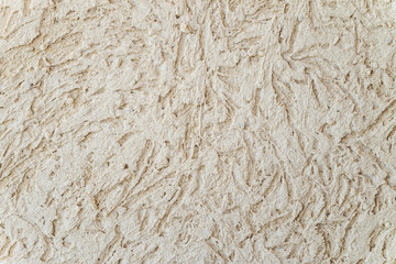 Beige surface plaster with relief texture at bark beetle style. Close-up.
