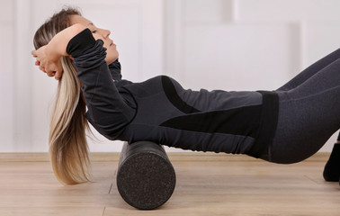 Mindful workout holistic health care. Woman doing foam roller exercises to relieve back pain