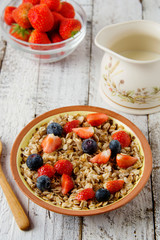 Healthy Homemade Oatmeal with Berries - fresh strwberries and blueberries, for Breakfast. Rustic white wooden table.