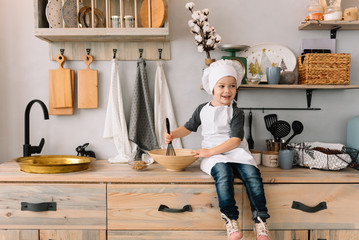 Young boy cute on the kitchen cook chef in white uniform and hat near table. the boy cooked the chocolate cookies