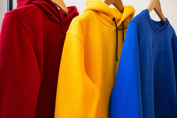 Colorful hoodies on hangers close-up modern design
