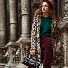 Outdoor fashion portrait of woman wearing trendy animal, leopard print faux fur coat, beret,...