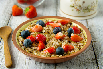 Healthy Homemade Oatmeal with Berries - fresh strwberries and blueberries, for Breakfast. Rustic white wooden table.