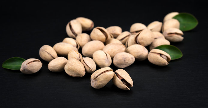 Handful of pistachios on a black background - healthy snack.