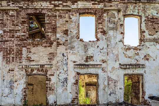 Brick wall with window openings of old abandoned dilapidated historical residential building