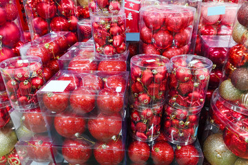 Sale of Christmas toys in the supermarket. Balls of red colors for the Christmas tree on the supermarket shelves. Christmas toys for sale in the store. Variety of red glass balls