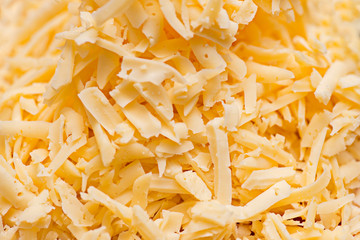 Grated cheese for a background. A very close view of shredded cheese