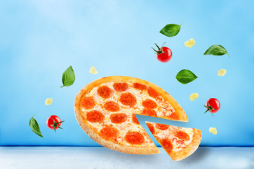 Pizza with pepperoni, tomato sauce and cheese on a blue background