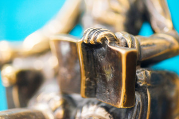 Closeup of the hand of a bronze statue holding an open book. Sculpture closeup. Small depth of field