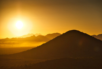 The sun rising over the mountains of the Arizona desert with natural warm hues.