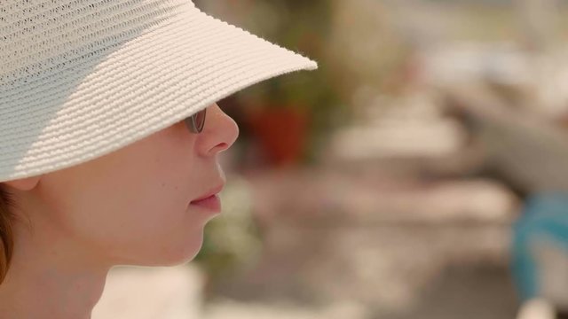 Close-up face of young tourist woman wearing hat and sunglasses relaxing on beach side view of pretty fashion female traveler enjoying vacation at summer sunny day