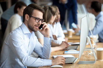 Confident employee talking, consulting by phone with client, sitting at workplace, customer, office...