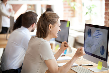 Happy smiling businesswoman looking at screen, economic report with graphics and diagrams,...