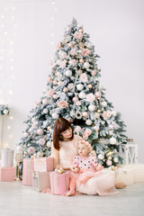 happy mother and baby daughter playing home on Christmas holidays. New Year's holidays. Toddler with mom in the festively decorated room with Christmas tree . Portrait of mother and baby daughter