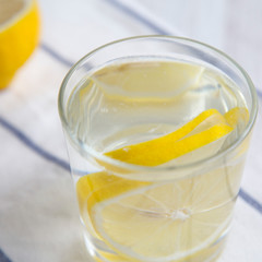 Water with lemon in glass on cloth, side view. Diet weight loss and healthy eating. Detox drink.