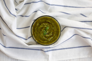 Basil pesto on cloth, overhead view. Flat lay, from above, top view.