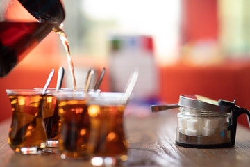 pouring tea into cup of coffee in kitchen