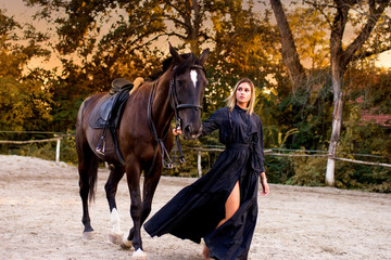  young beautiful woman walking with horse . Sunset.