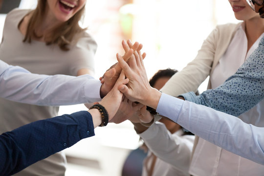 Excited happy multiracial team giving high five, celebrating good results, congratulating with success at briefing, group of employees rejoicing at achieved goal, good teamwork, collaboration, close
