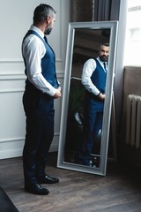 Elegant look. Full length of handsome man in full suit adjusting his jacket while standing in front...