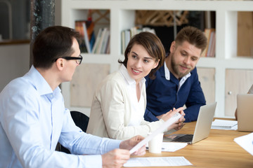Smiling woman looking at male colleague at briefing, company meeting, while working together in shared workspace, female employee attentively listen to coworker at training, team building