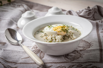 Sorrel soup with egg in white bowl.