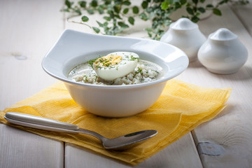 Sorrel soup with egg in white bowl.