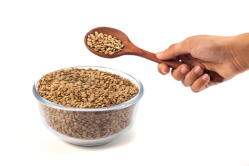 dry lentil in glass bowl with wooden spoon in the hand isolated on white background