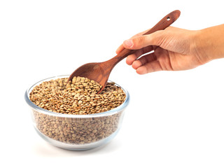 dry lentil in glass bowl with wooden spoon in the hand isolated on white background