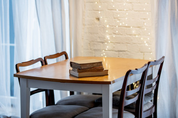 Three boooks on a table in a kitchen. Christmas lights on background