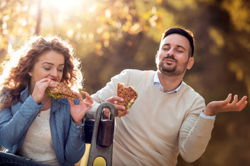 Obraz premium Couple eating sandwich in city park