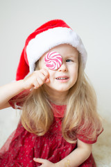 Little Beautiful Girl in Santa Hat Red Party Dress Waiting for Christmas and New Year Indoor Happy