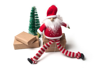 closeup of little santa claus sitting on gifts on white background