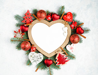 Christmas frame in the shape of a heart is surrounded by branches of a New Year tree Christmas decorations with copy space. Top view, flat lay. Nature New Year concept.