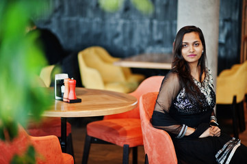 Pretty indian girl in black saree dress posed at restaurant.