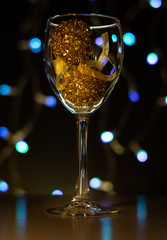 Christmas cards. Wine glass with red, blue and gold Christmas decorations on dark background with christmas tree garland.