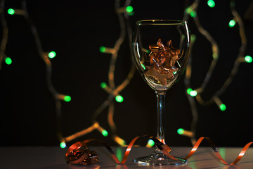 Christmas cards. Wine glass with red, blue and gold Christmas decorations on dark background with christmas tree garland.