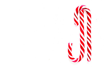 Candy canes on a white surface, top view, place for text