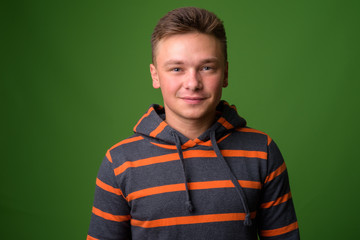 Studio shot of young handsome man against green background