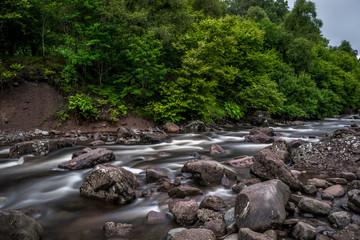 Wild Mountain River Streaming Through Green Forest in Scotland