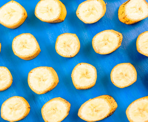 Sliced banana pattern on blue background, wooden table.