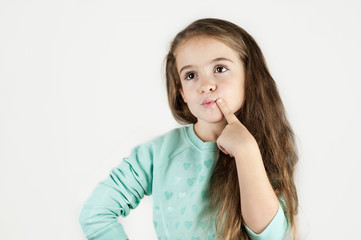 Little bright beautiful girl emotionally posing on an isolated turquoise background