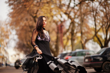 Fototapeta na wymiar Pretty indian girl in black saree dress posed outdoor at autumn street.