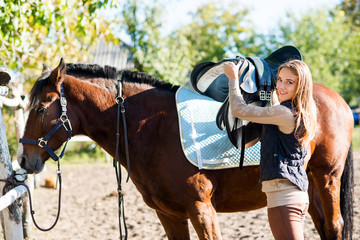 Girl equestrian rider equips horse. Horse theme