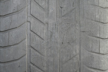 Old black tire with worn tread and cracks, worn old car tire tread, old damaged, worn black tire tread, large cracks in the car wheel, tire black color for background.