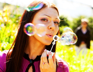 girl blow soap bubble against a background grass