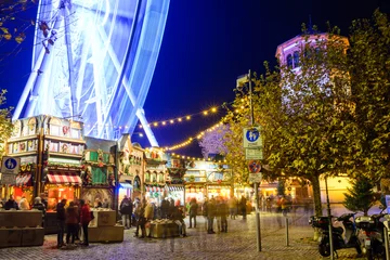 Night colorful atmosphere of Weihnachtsmarkt, Christmas market, in Düsseldorf, the ferris wheel and christmas theme decorated booths set up at the old town. © Peeradontax