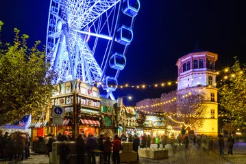 Nächtliche bunte Atmosphäre des Weihnachtsmarktes, Weihnachtsmarkt, in Düsseldorf, das Riesenrad und weihnachtlich geschmückte Stände in der Altstadt. © Peeradontax
