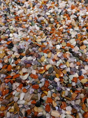 Many little colorful stones. Colorful mix of polished gemstones and minerals. Close-up, background, texture.